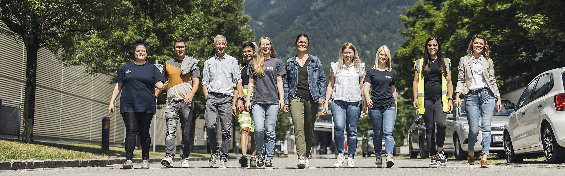 Mehrere Mitarbeitende gehen auf den Fotografen zu. Im Hintergrund Berge